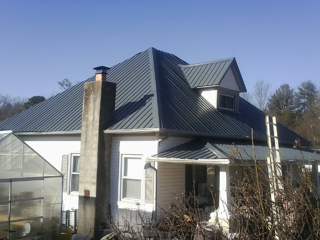 Dark blue standing seam metal roof on a white farmhouse with dormer — Slate & Tile Roof Repair by Roofing Brothers in Cecil